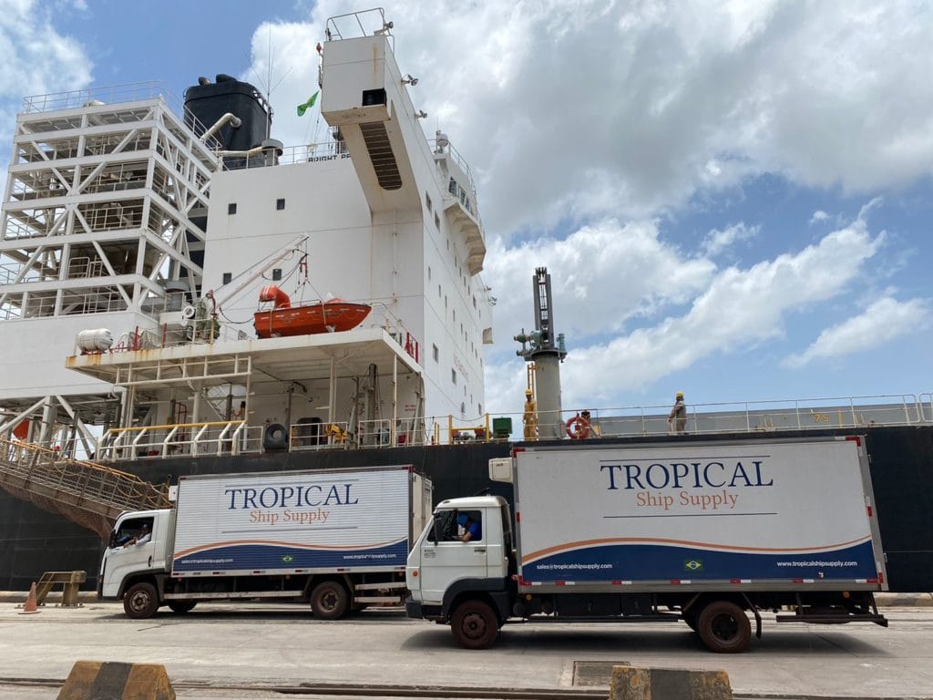 Two Tropical Ship Supply refrigerated trucks alongside a vessel at the berth