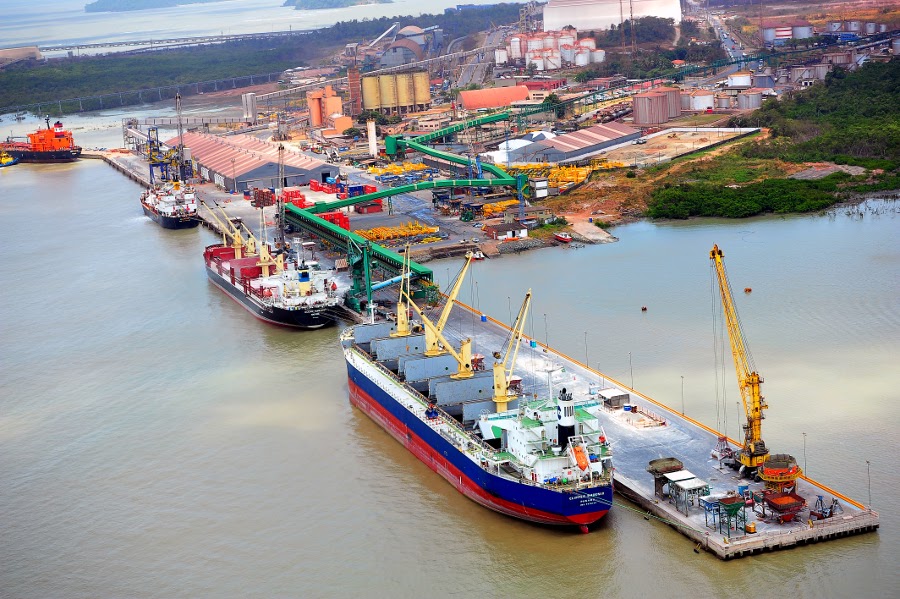 Container ship docked at a Brazilian port with cranes and supply trucks