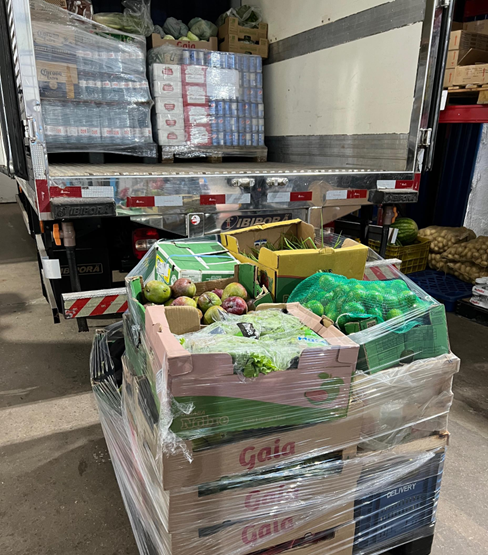 Crew unloading refrigerated containers from supply truck to cargo vessel at sunrise