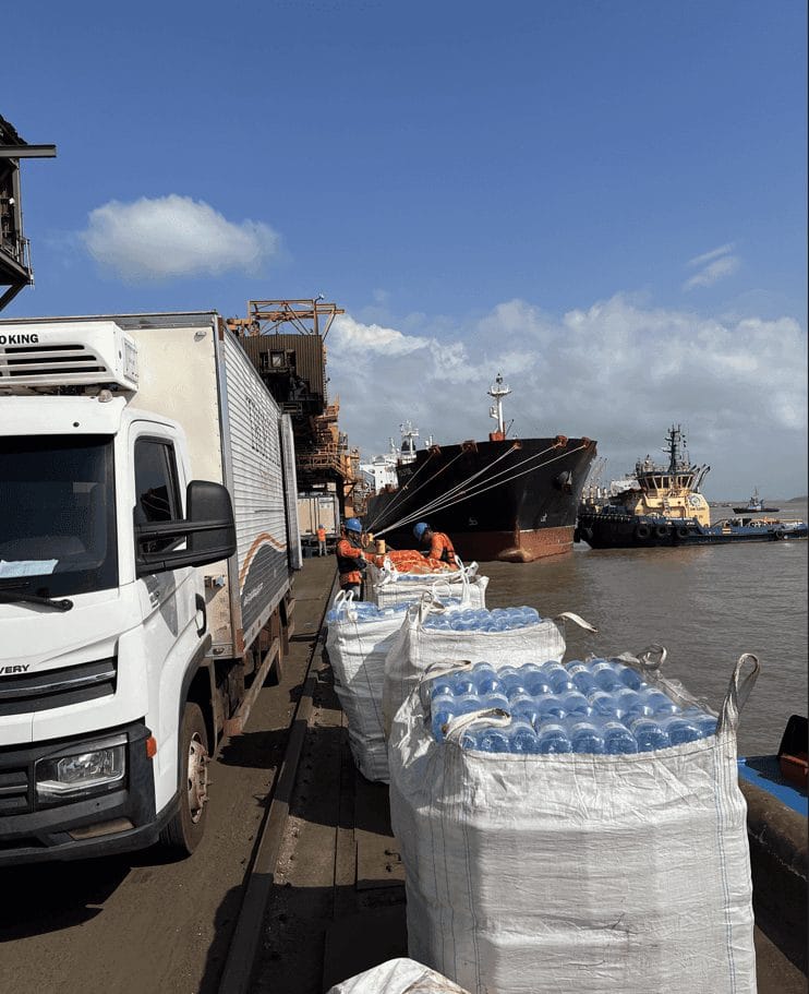 Pallets of bottled water on the quay beside Tropical Ship Supply trucks