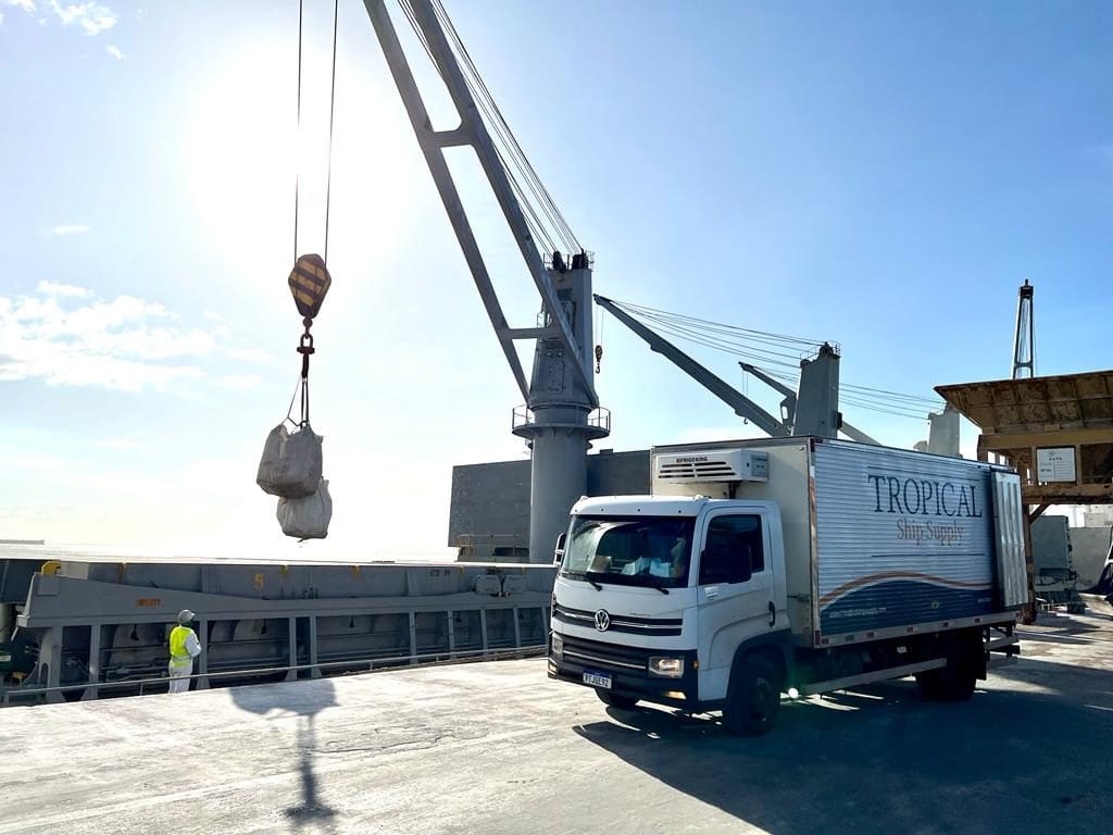 Ship crane lifting stores on board from a Tropical Ship Supply refrigerated truck