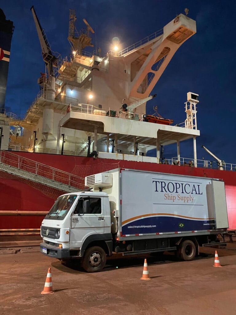 Refrigerated truck delivering ship stores alongside a vessel at night